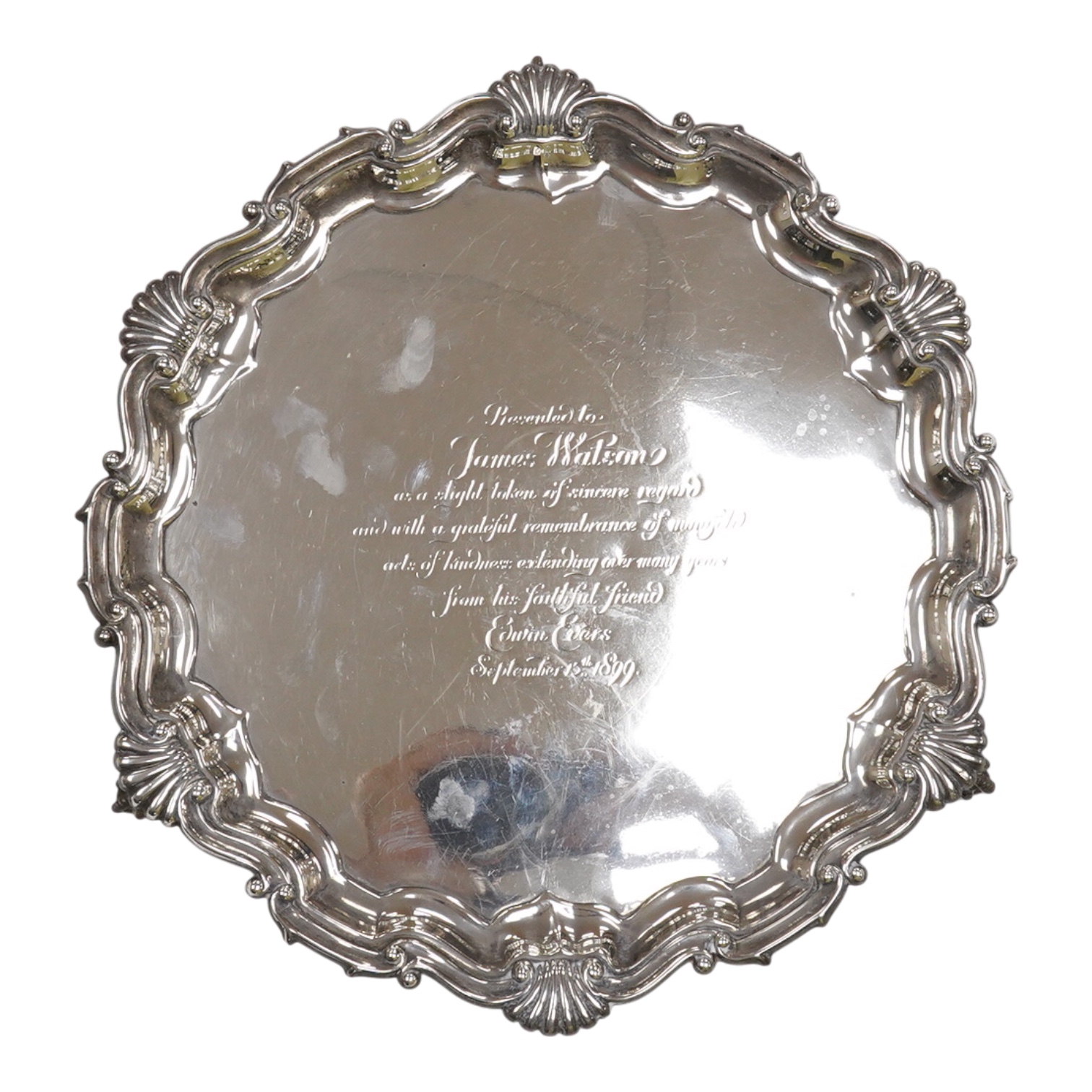 A late Victorian silver salver, with shell and scroll border and engraved inscription, on three claw and ball feet, Mappin Brothers, Sheffield, 1896, 26.4cm, 15.2oz.